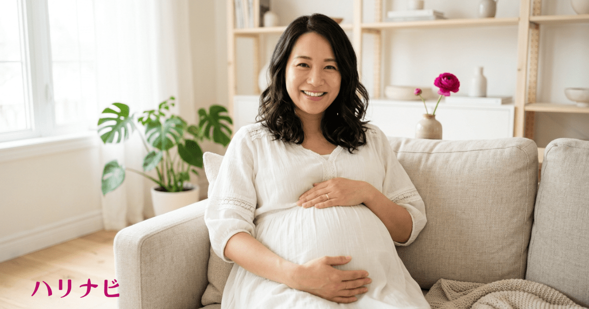笑顔でお腹に手を当てている妊婦さんのイメージ写真