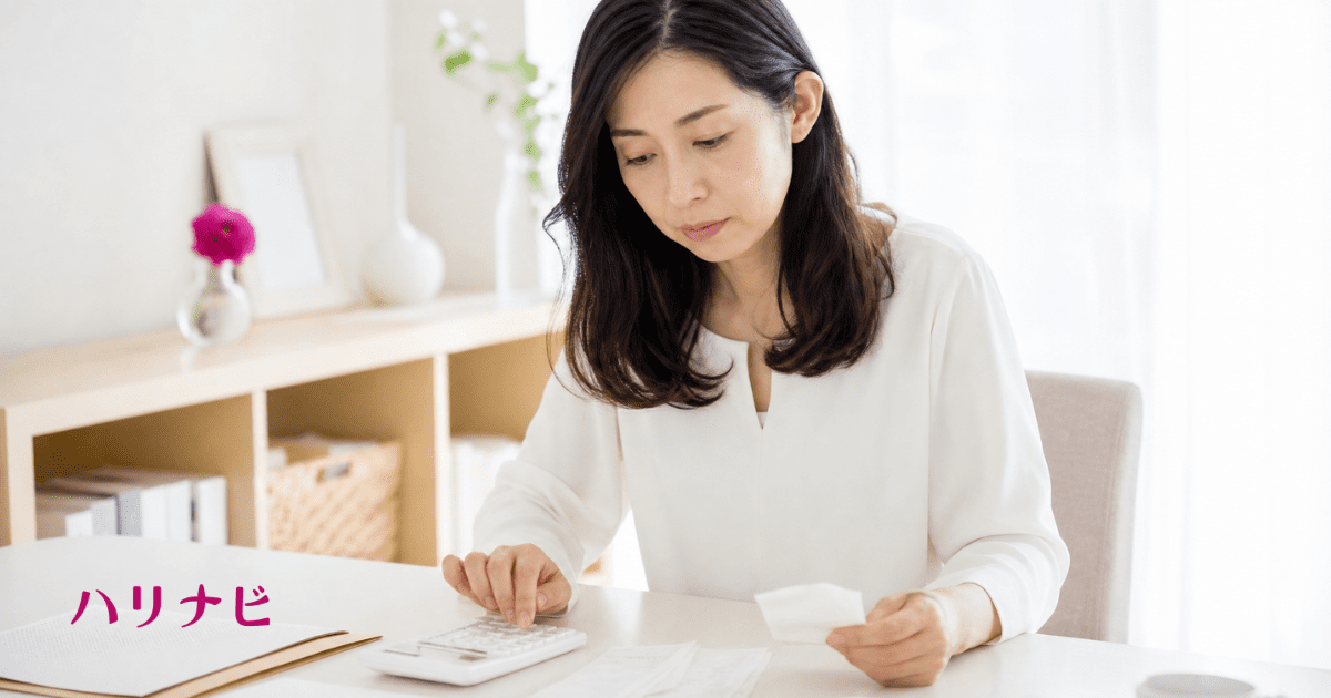 電卓と領収書を前に確定申告の書類を確認する女性のイメージ