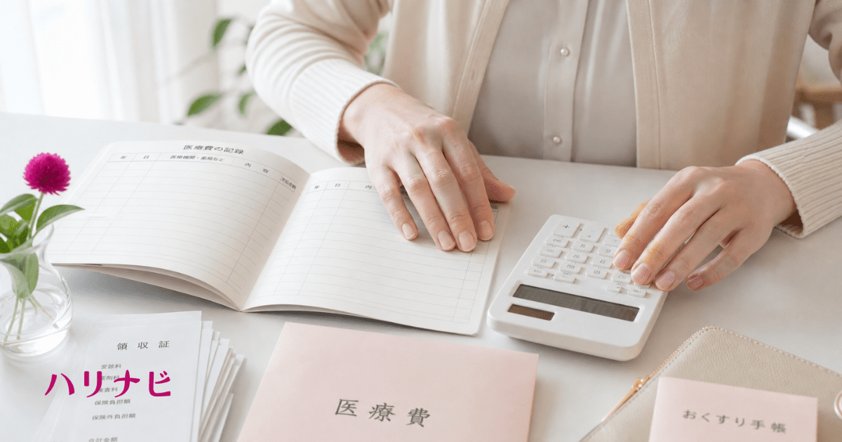 家計簿と電卓を使って医療費を計算する女性の手元