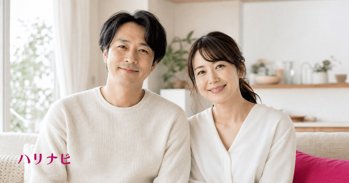 朝の光が差し込むリビングで前向きな表情で並んで座る夫婦