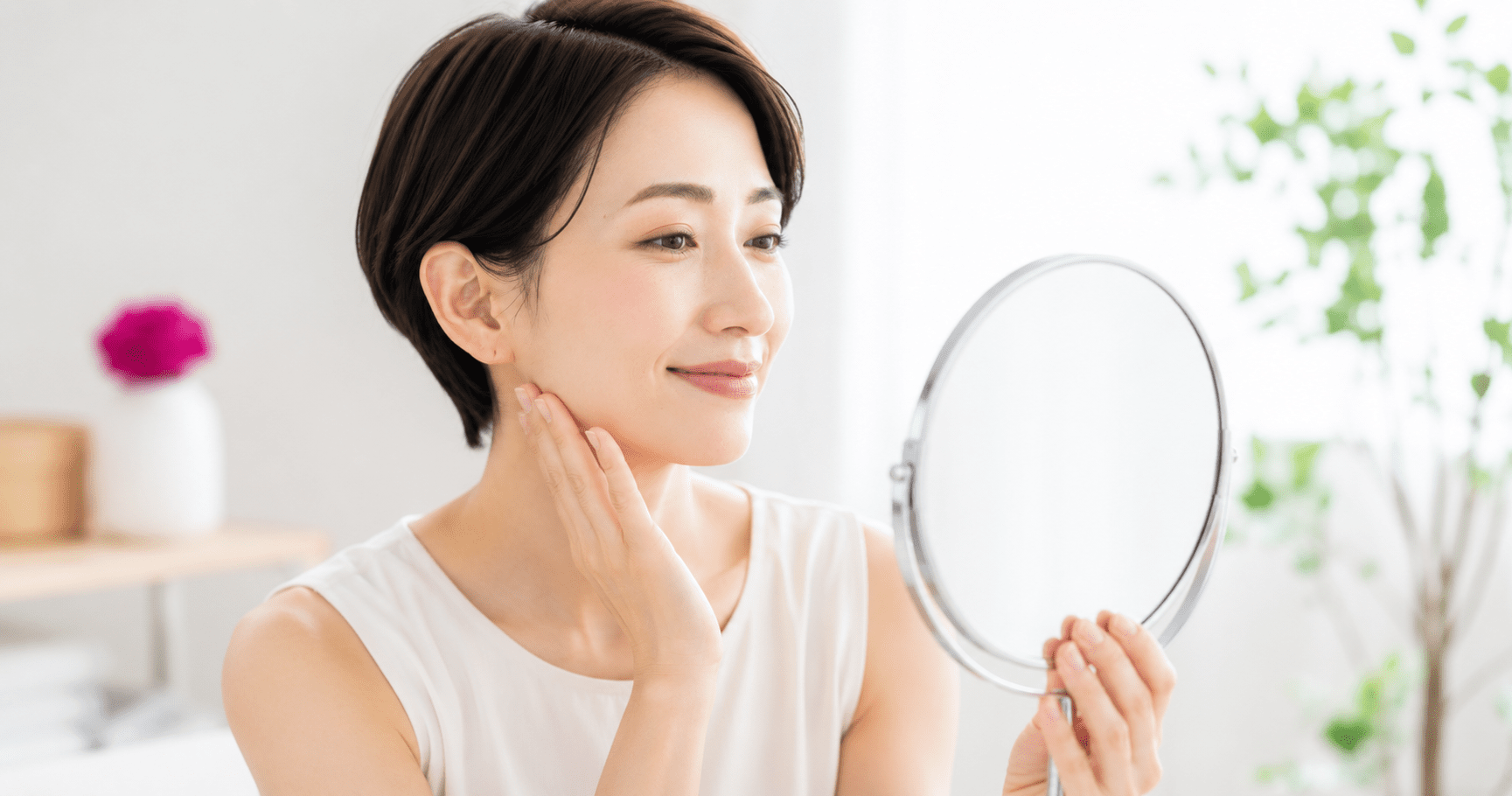 食いしばりがやわらいだ後のすっきりとしたフェイスラインを鏡で確認する女性
